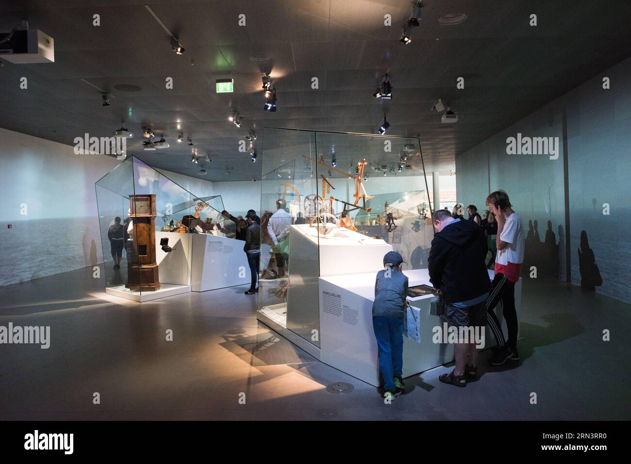M/S Maritime Museum manufatti marittimi Helsingor Denmark // HELSINGOR, Danimarca — i visitatori del museo esaminano manufatti storici marittimi, tra cui attrezzature di navigazione e strumenti di cronometraggio presso il M/S Maritime Museum of Denmark. La mostra mette in mostra strumenti e tecnologie essenziali per la vita marittima e la navigazione marittima. Questi manufatti fanno parte della vasta collezione del museo che documenta il patrimonio marittimo danese. Foto Stock