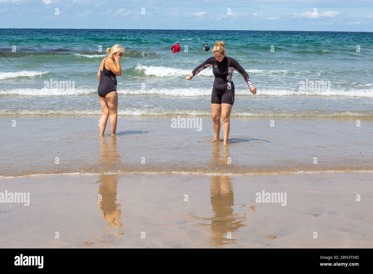 Una nuotatrice donna lascia le fredde acque di Trevaunance Cove , St Agnes , Cornovaglia, Regno Unito , Foto Stock