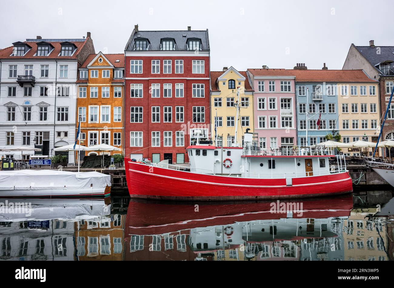 COPENAGHEN, Danimarca - Nyhavn, lo storico porto di Copenaghen, è visto animato da attività. Un tempo porto commerciale dove attraccavano navi da tutto il mondo, Nyhavn è ora un luogo di ritrovo culturale pieno di ristoranti, bar e case tradizionali, segnando la sua trasformazione da vivace centro marittimo a principale attrazione turistica. Foto Stock