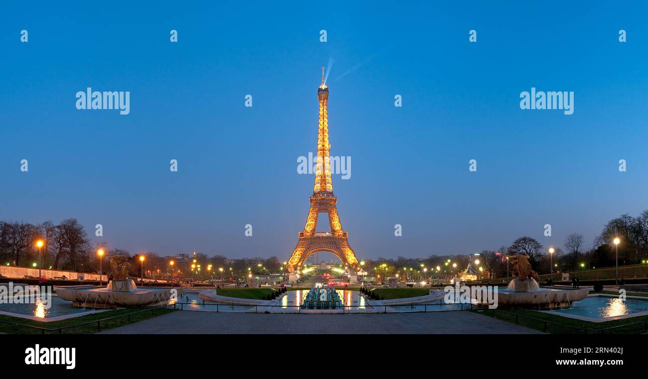 Torre Eiffel illuminata di notte Parigi Francia // PARIGI, Francia - la Torre Eiffel è illuminata contro il cielo serale in questa foto panoramica ad alta risoluzione della capitale francese. La torre di ferro, completata nel 1889 per l'esposizione universale, fu progettata dall'ingegnere Gustave Eiffel e originariamente serviva come arco d'ingresso alla fiera mondiale. Con un'altezza di 330 metri (1.083 piedi), la struttura fu inizialmente concepita come installazione temporanea, ma divenne un simbolo permanente di Parigi. La torre si trova sul campo di Marte nel settimo arrondissement e attira milioni di persone Foto Stock