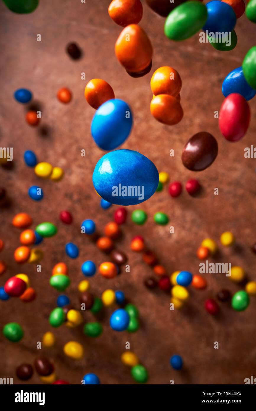 Immagine piena di caramelle di vari colori cadenti su uno sfondo marrone scuro dalla vista dall'alto. Foto Stock