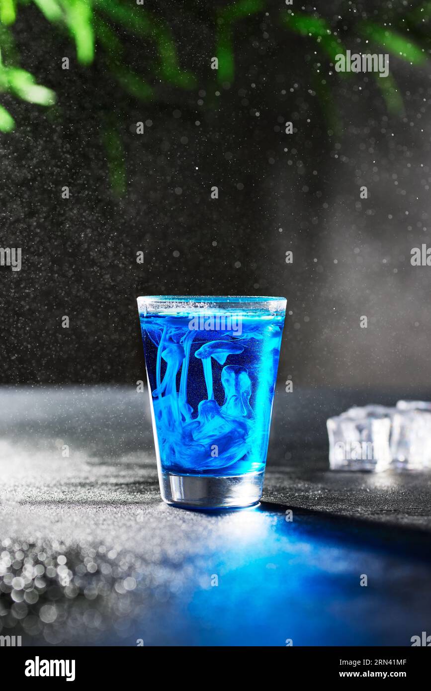 Blue Jelly fish shot alcolico su uno sfondo di pietra grigio scuro. Ci sono gocce di ghiaccio e pioggia che donano un'atmosfera rinfrescante all'immagine. Foto Stock
