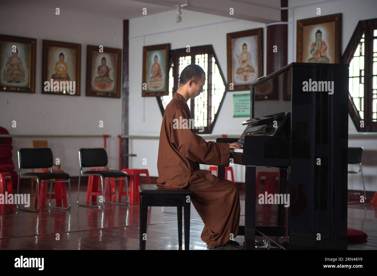 Un monaco pratica il pianoforte nel Tempio di Tiantai nella contea di Hong An, nella provincia di Hubei nella Cina centrale, 8 maggio 2015. I monaci del Tempio di Tiantai sono competenti non solo nel dharma del Buddha, ma anche negli strumenti orchestrali. Il Maestro Wule ha iniziato a ricostruire il Tempio di Tiantai, vecchio di 1400 anni, dal 2004. Come ex musicista, organizzò l'orchestra monaca Guangxuan per predicare il buddhismo e la filosofia Zen attraverso la musica nel 2008. I membri dell'orchestra imparano a suonare strumenti da zero e a superare numerose difficoltà. Attirando credenti e monaci che si identificano con l'idea della pratica buddista attraverso Foto Stock