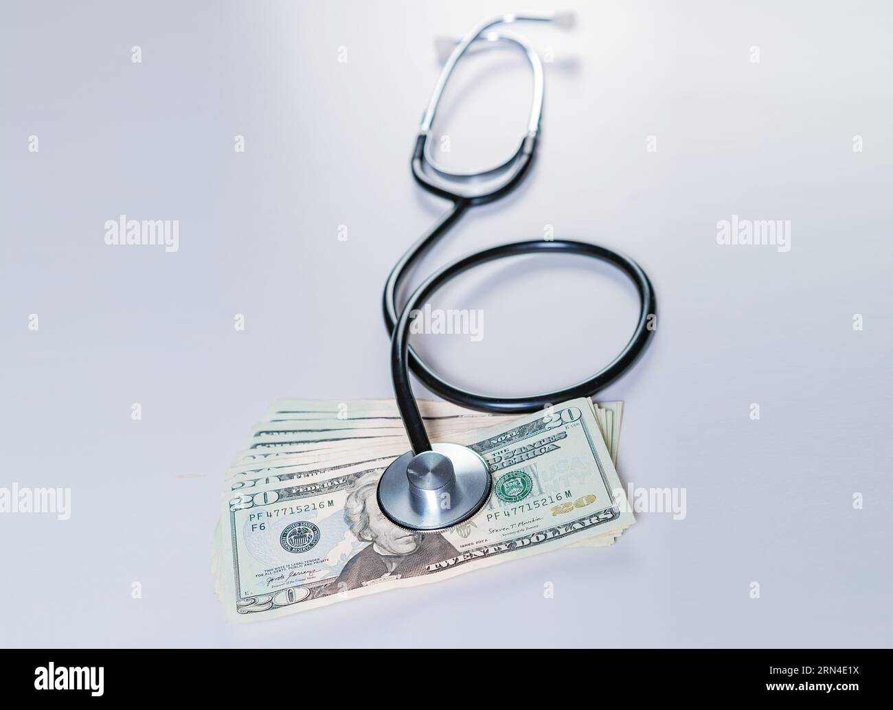 Stetoscopio isolato sulle banconote in dollari. Stetoscopio sulla parte superiore di banconote di dollaro isolato, concetto di costo medico Foto Stock