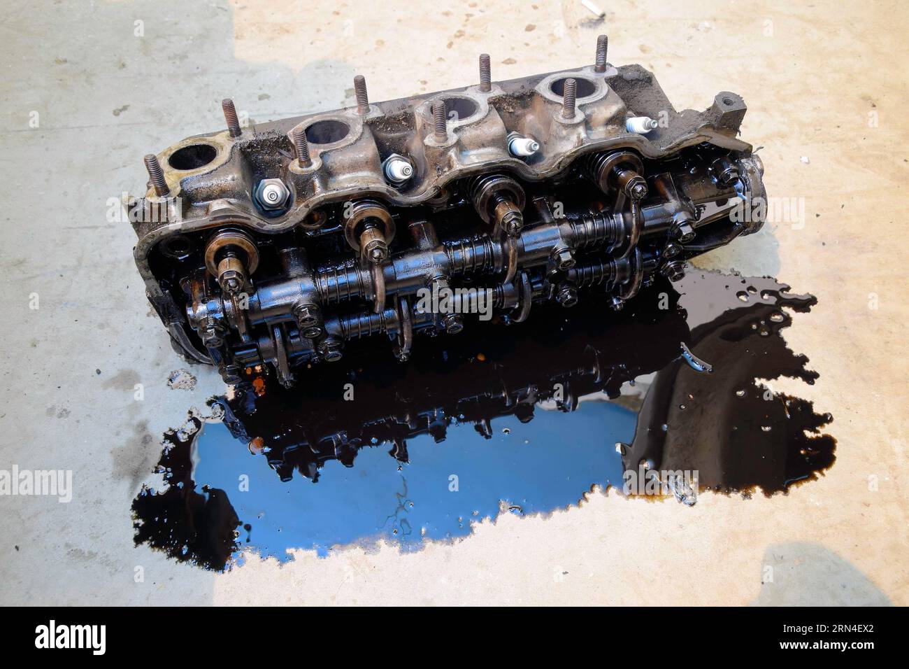 La testa del blocco dei cilindri. La testa del blocco dei cilindri rimosso dal motore per la riparazione. Parti in olio motore. Motore auto riparazione in t Foto Stock