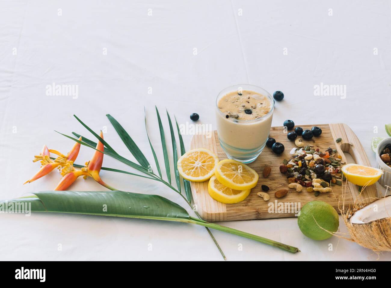 Frullato floreale con frutti secchi e agrumi su sfondo bianco Foto Stock