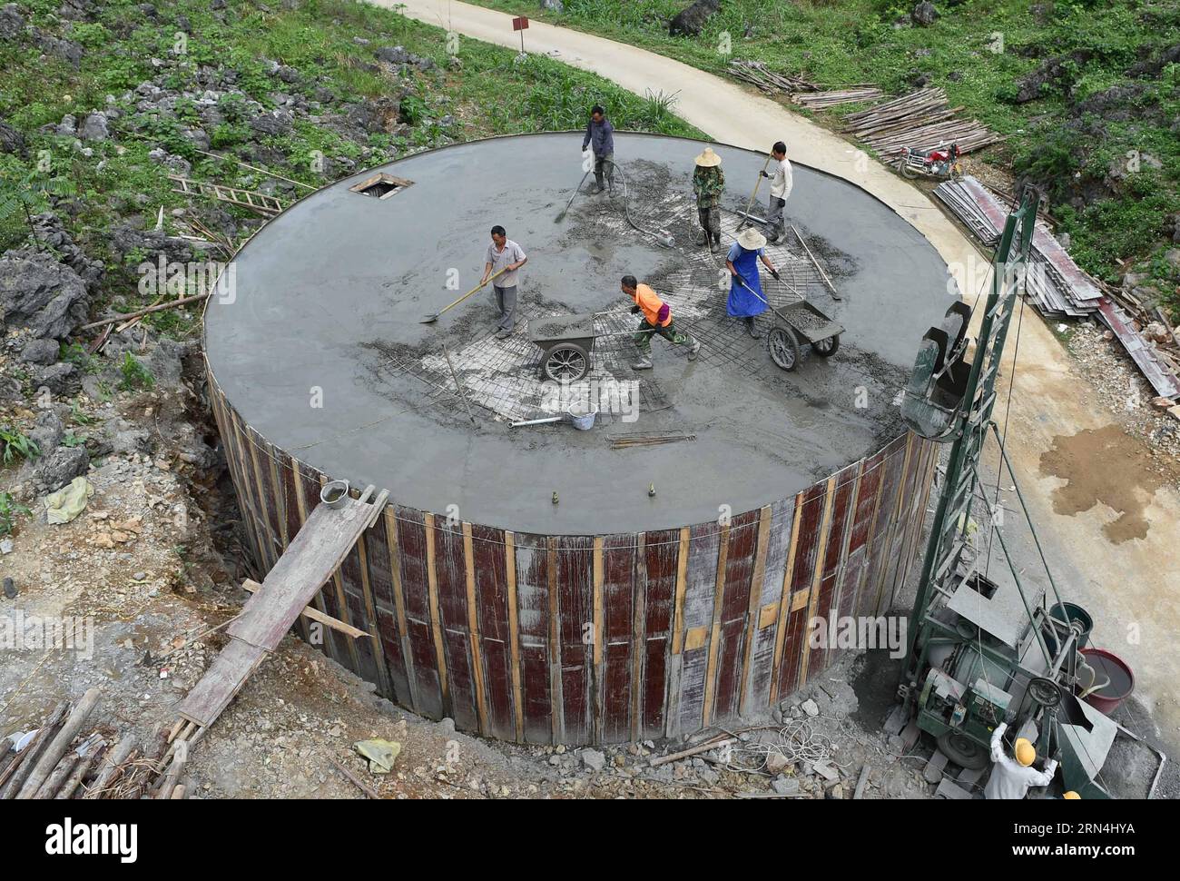 La gente costruisce un serbatoio d'acqua di 300 metri cubi finanziato dal governo locale nel villaggio di Nongyong della municipalità di Bansheng nella contea autonoma di Dahua Yao, nella regione autonoma di Guangxi Zhuang della Cina sud-occidentale, il 6 maggio 2015. Situata al centro delle formazioni rocciose del Carso nel Guangxi occidentale, la città di Bansheng soffre di un grave deficit idrico per secoli. Le precipitazioni sono quindi una benedizione per le persone che vivono in questa terra per circa 1.000 anni, che appartengono principalmente al gruppo etnico Yao. Per soddisfare le loro esigenze quotidiane, la gente del posto raccoglie sempre acqua piovana con secchi e barili di tutte le dimensioni, oltre che tetti di Th Foto Stock