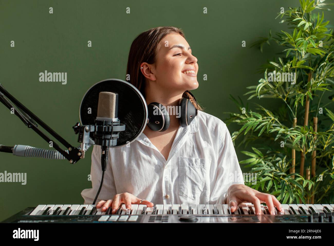 Vista frontale musicista femminile sorridente che suona una tastiera per pianoforte all'interno Foto Stock