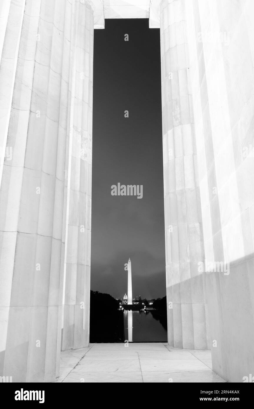 Monumento a Washington dal Lincoln Memorial, National Mall, Washington DC - foto in bianco e nero | WASHINGTON D.C., Stati Uniti - il monumento a Washington brilla di notte come si vede attraverso le colonne del Lincoln Memorial, con la cupola del Campidoglio degli Stati Uniti ben visibile oltre. Completato nel 1884, l'obelisco di marmo sorge a 169 m (555 piedi), allineato lungo l'asse centrale del centro commerciale con il Campidoglio e il Memoriale. Foto Stock