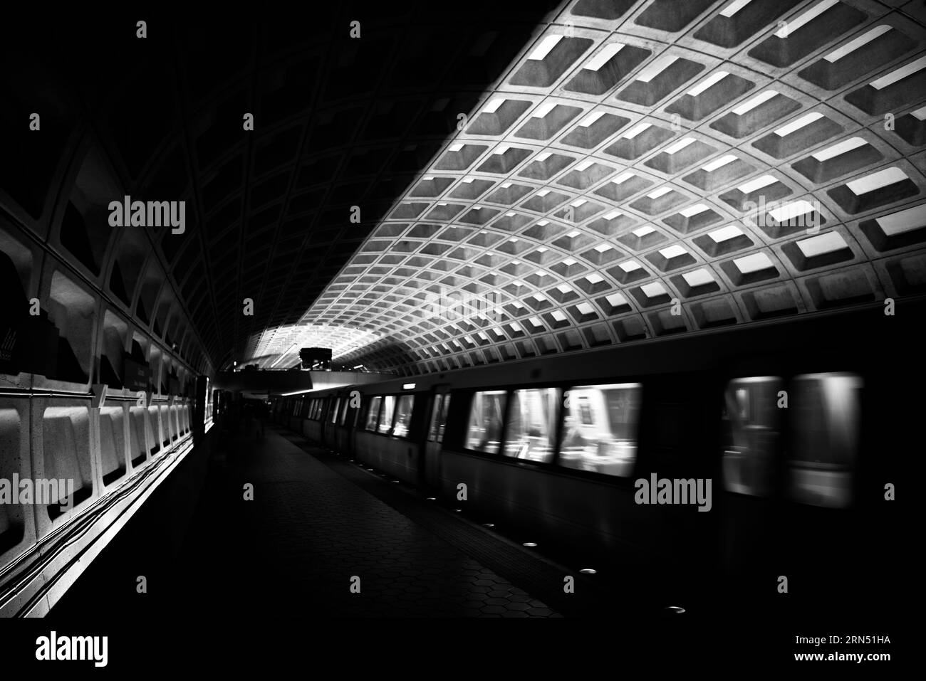 Binario della stazione della metropolitana, Washington, D.C. Fotografia in bianco e nero che mostra il soffitto a cassettoni e un treno in movimento lungo il binario. Foto Stock