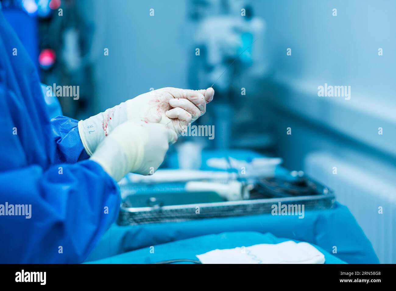 Un medico trattiene il filo di sutura durante un'operazione in ospedale Foto Stock