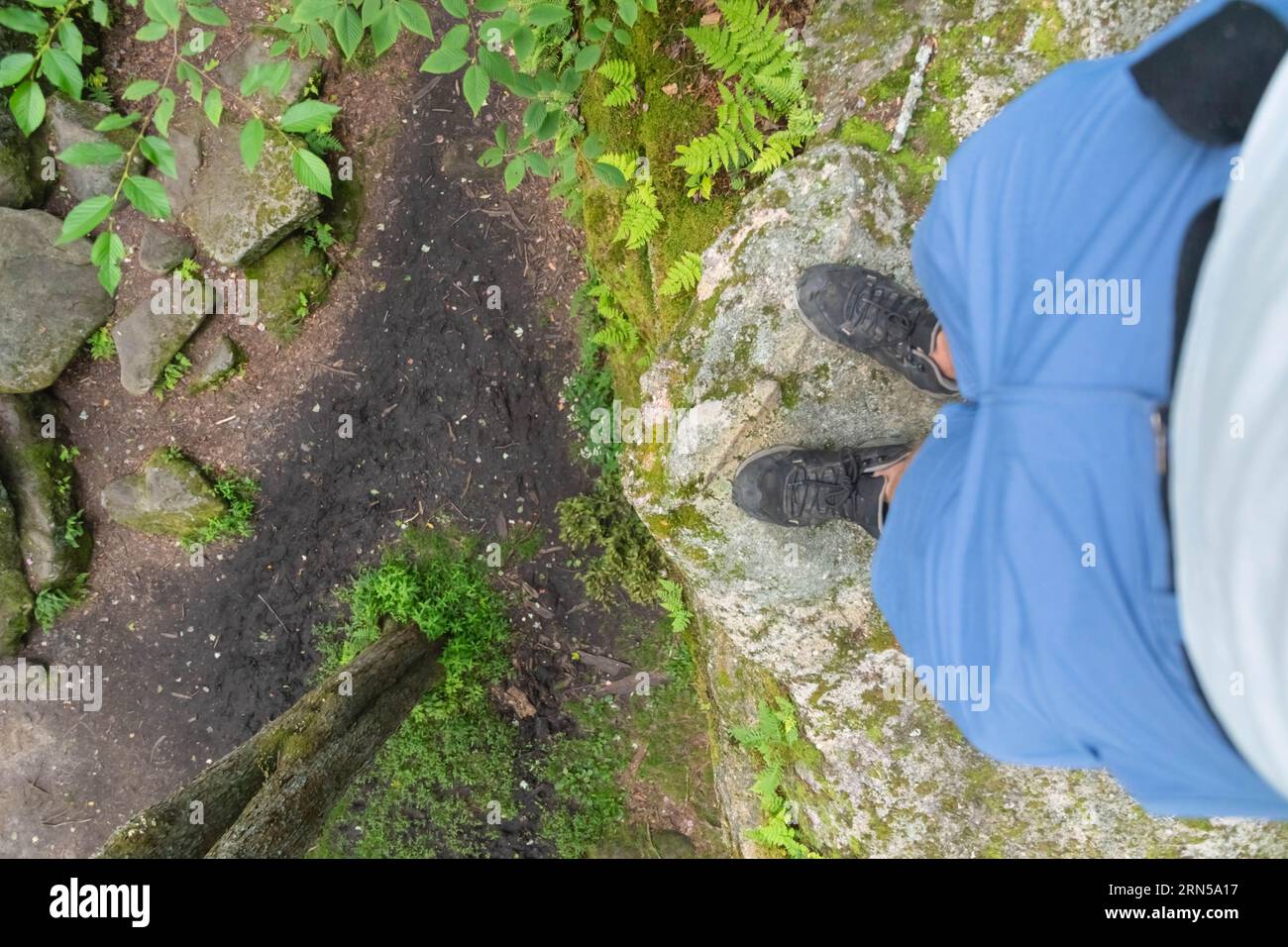 Escursionista che guarda in basso da un bordo di un masso di pietra Foto Stock