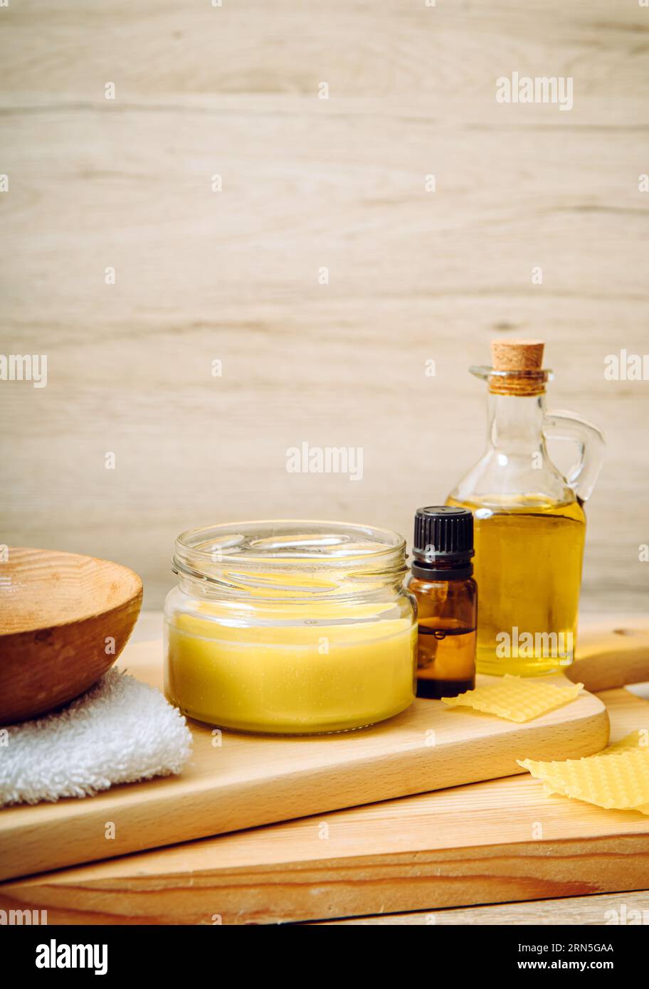 Cera d'api fatta in casa per il trattamento del legno lucido, restaurare mobili in legno naturale, piatti, tagliere. Cera d'api, olio d'oliva e olio essenziale, panno morbido. Foto Stock