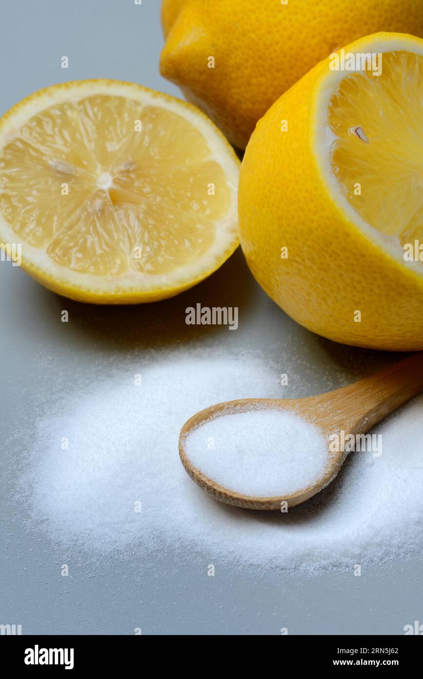 Acido citrico in cucchiaio di legno e limone Foto Stock