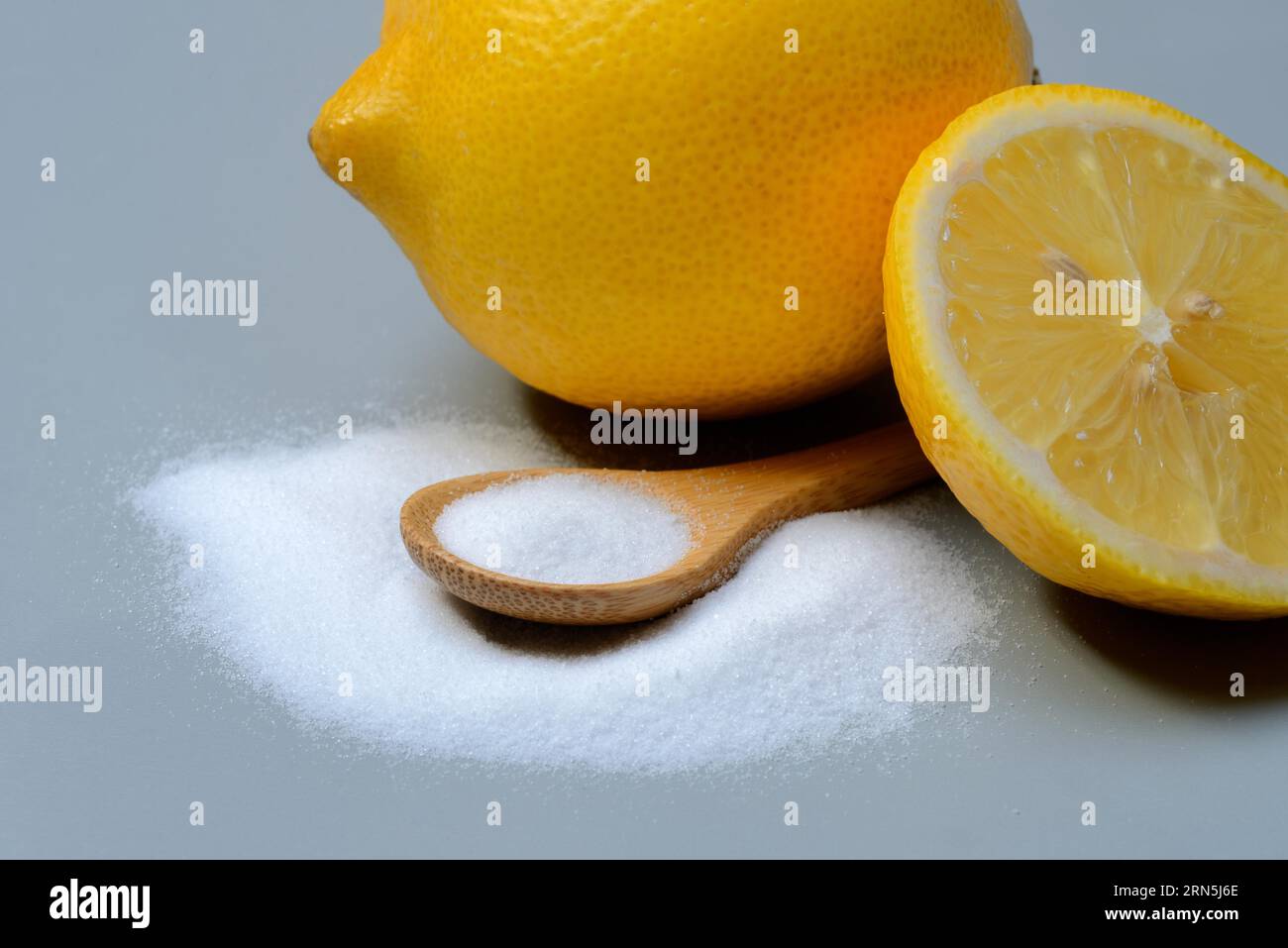 Acido citrico in cucchiaio di legno e limone Foto Stock