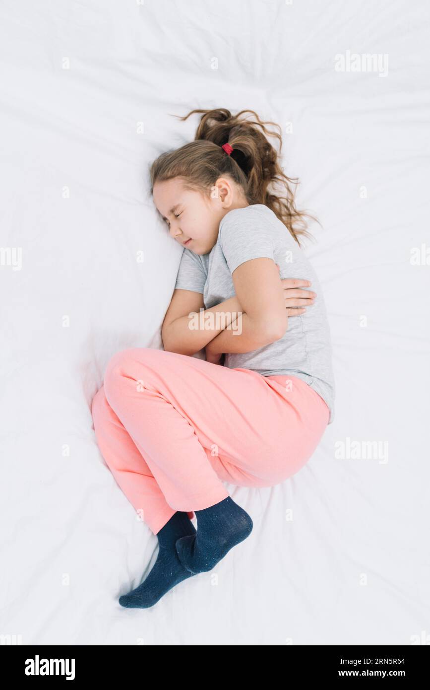 Vista elevata ragazza malata che indossa calzino con dolore allo stomaco Foto Stock