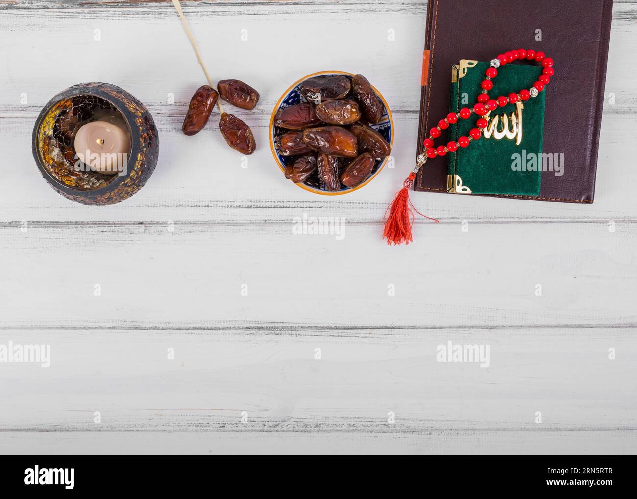 Succosa ciotola di datteri secchi diario di candele rosario islamico curano perline di preghiera scrivania in legno bianco Foto Stock