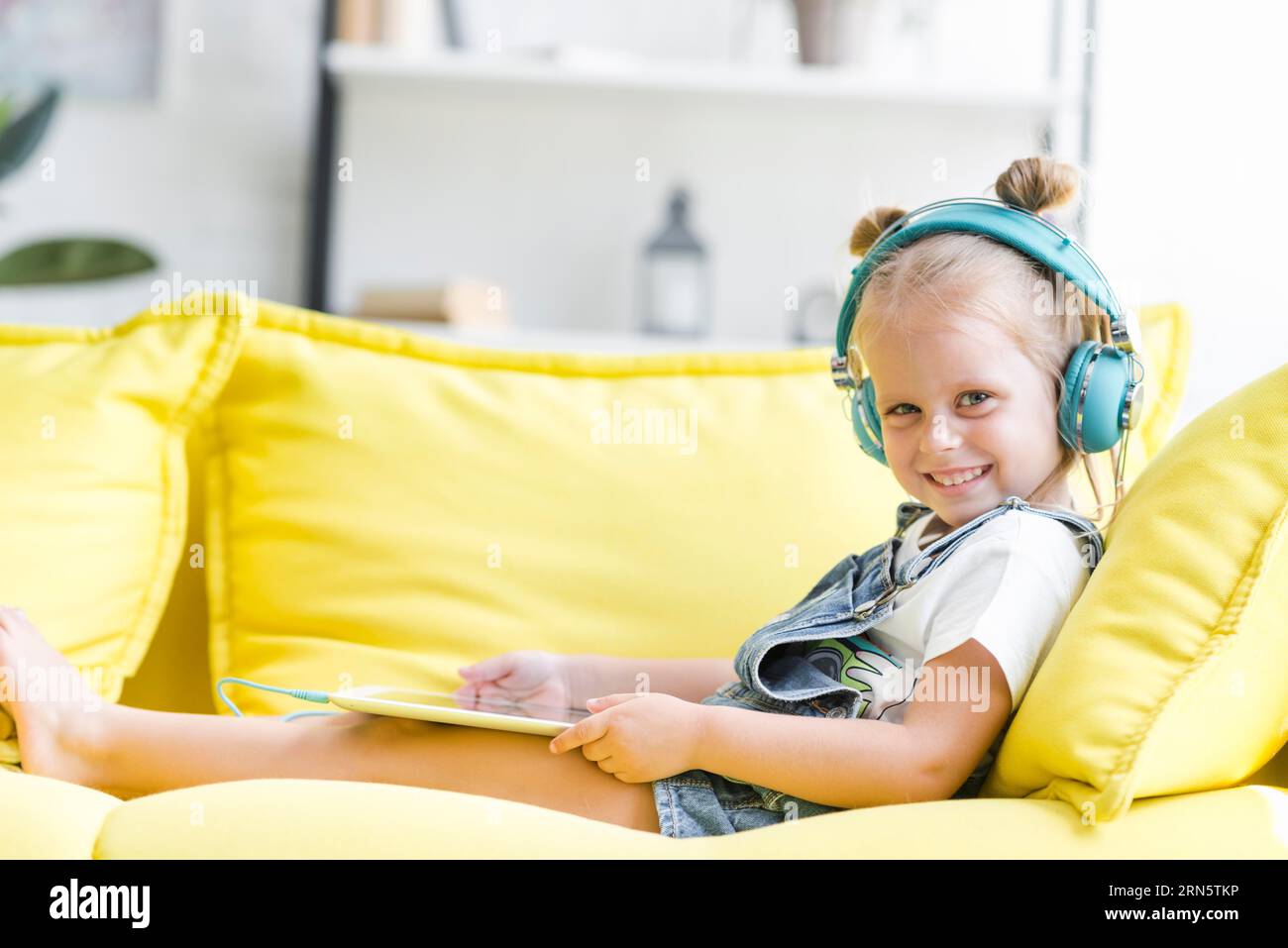 Cuffie per bambina sorridenti che ascoltano musica con un tablet Foto Stock