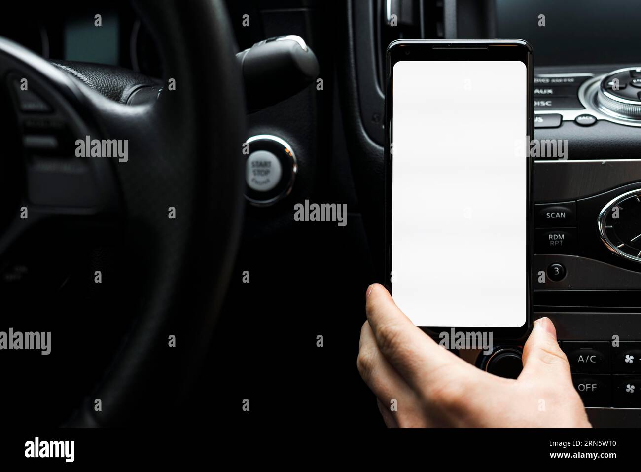 Avvicinare la mano tenendo lo smartphone con lo schermo bianco dell'auto Foto Stock