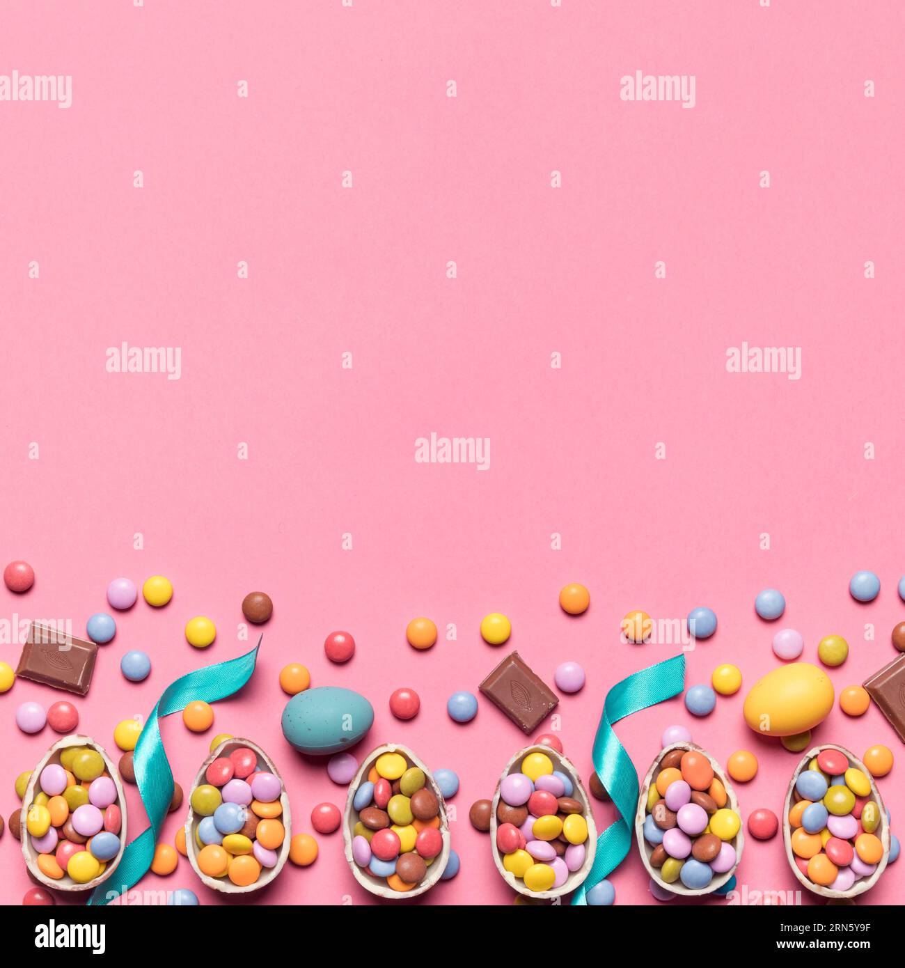 Nastro gemma caramelle uova di pasqua con spazio scrittura sfondo rosa testo Foto Stock