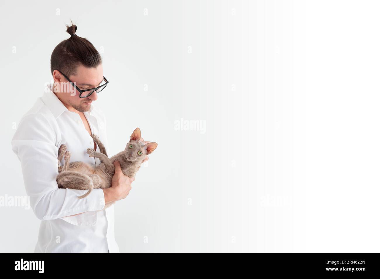 Joung uomo che tiene un gatto cornish rex tra le braccia. Banner Foto Stock