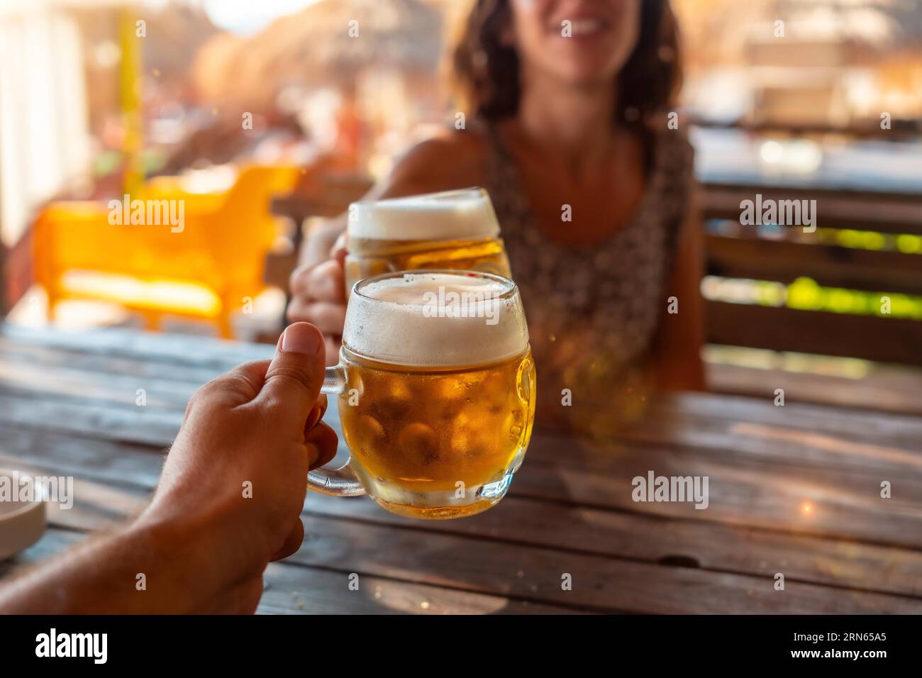Brindisi di una coppia sulla spiaggia in estate bevendo qualche birra in una celebrazione dell'amicizia Foto Stock