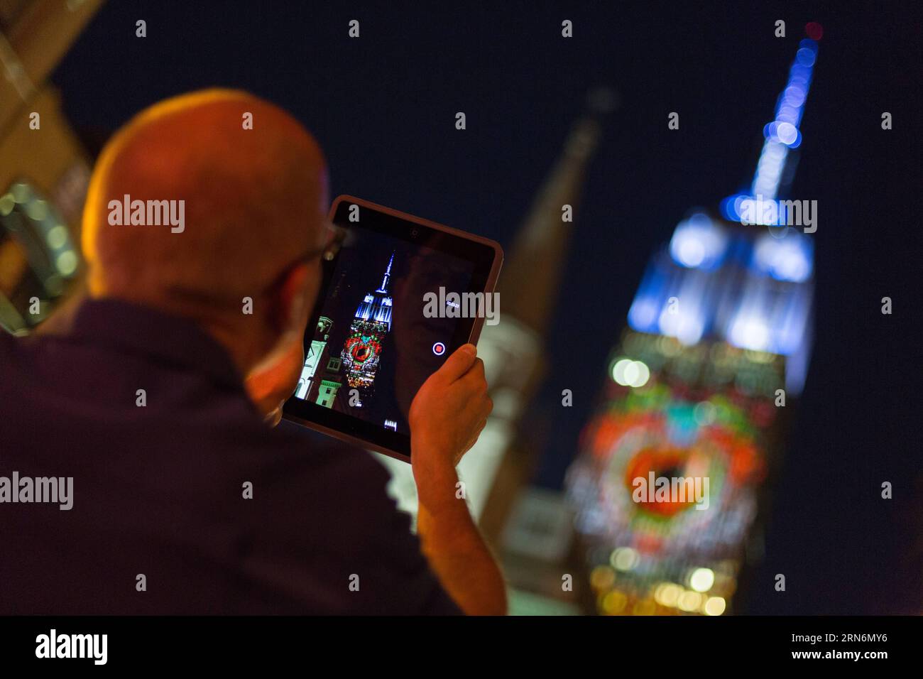 (150802) -- NEW YORK, - Un uomo registra video di proiezioni di luce digitali delle specie a rischio di estinzione del mondo sulla facciata sud dell'Empire State Building nel quartiere di Manhattan, New York City, Stati Uniti, 1 agosto 2105. L'edificio storico Empire State Building risplende brillantemente con proiezioni di luce digitale delle specie a rischio di estinzione del mondo sabato sera. Lo spettacolo è stato pubblicizzato come una proiezione video live unica nel suo genere e mirava a sensibilizzare gli animali a rischio di essere persi per sempre. L'esposizione, un progetto ideato dal regista di Cove Louie Psihoyos, mostrava un avvolgimento di pericolo Foto Stock