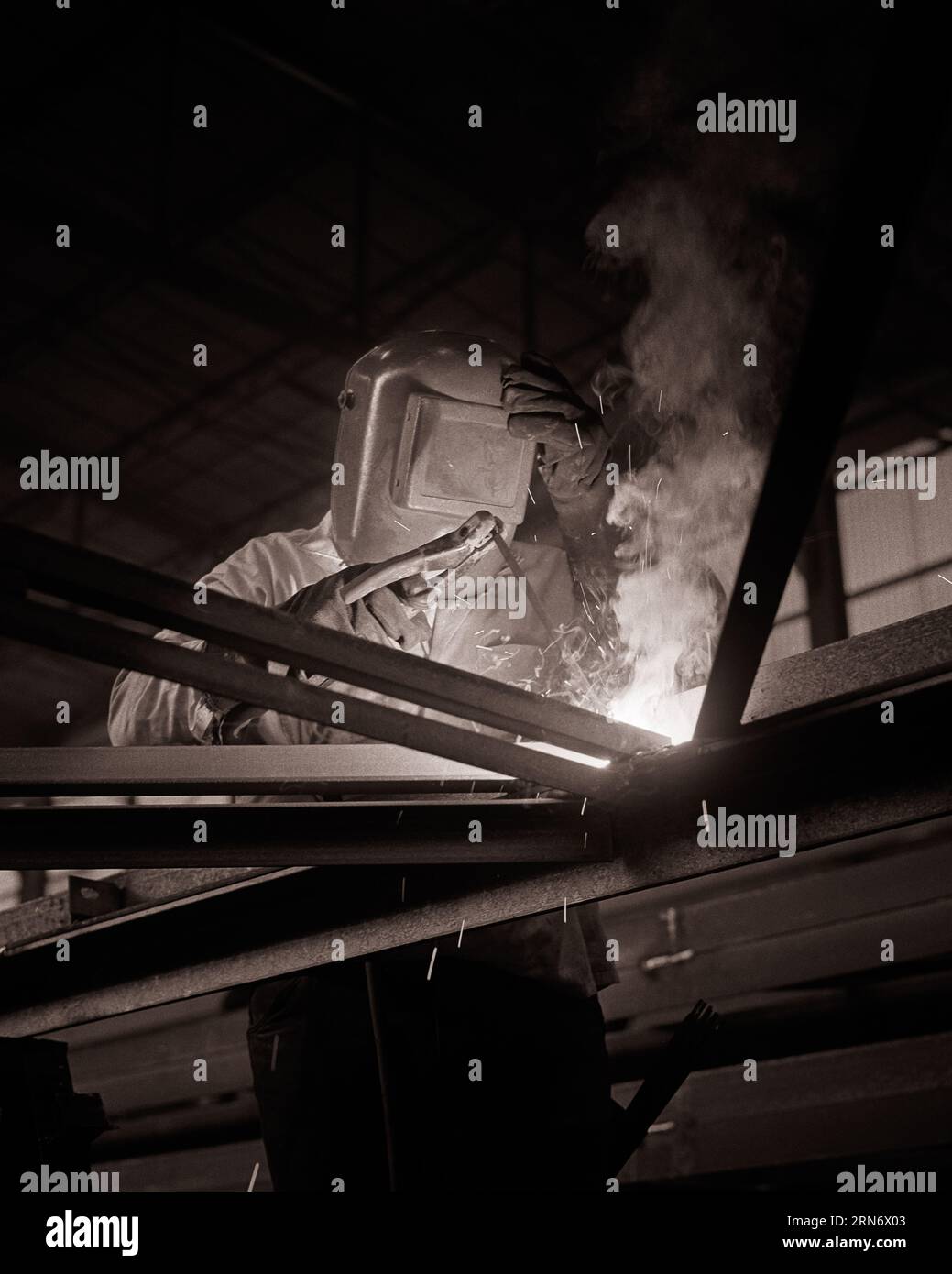 SALDATRICE ANONIMA DEGLI ANNI '1970 LAVORO CON GUANTI CASCO IN CANTIERE - I6333 HAR001 HARS SCINTILLE SALDATORE IMPIEGO RISCHIOSO OCCUPAZIONE PERICOLOSA SALDATURA DIPENDENTE ANONIMO COMMERCIANTE BIANCO E NERO HAR001 CHE LAVORA IN VECCHIO STILE Foto Stock