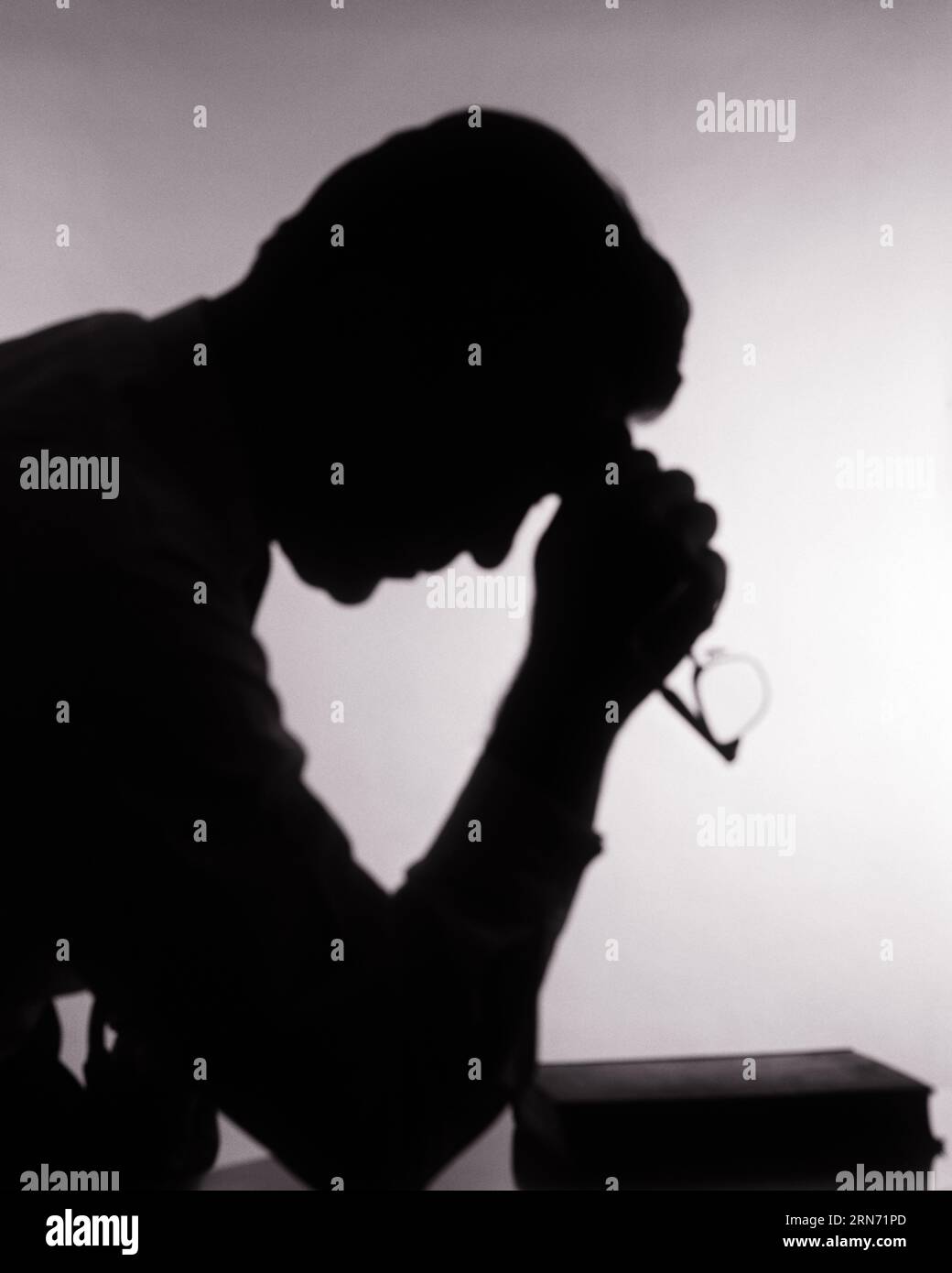 SILHOUETTE ANONIMA DEGLI ANNI '1960 CON UOMO TORMENTATO, MANO A FRONTE, OCCHIALI CON BIBBIA SUL TAVOLO IN PREGHIERA - R19563 HAR001 HARS SPIRITUALITÀ MASCHILE TURBATA B&W PREOCCUPATA TRISTEZZA DEVOZIONE TESTA E SPALLE PREGHIERA RELIGIOSA PENSIERO RIFLESSIVO UMORE MEDITAZIONE RIFLESSIVO RIFLESSO MEDITAZIONE RIFLETTERE LA CONNESSIONE MEDITAZIONE CONSIDERATE PERSI NEL PENSIERO SUPPORTO CONCETTUALE GLUM CONTEMPLATIVO ANONIMO FEDELE MEDITARE FEDE MEDITATIVA MISERABILE CREDENZA BIANCO E NERO CONSIDERANDO LA CONCENTRAZIONE HAR001 VECCHIO STILE Foto Stock