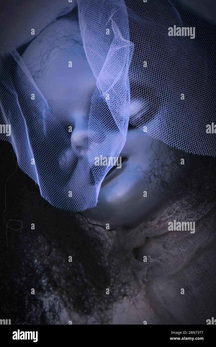 Bambola orrore vintage con occhielli bianchi che indossa un elegante cofano con velo. Sfondo di Halloween Foto Stock