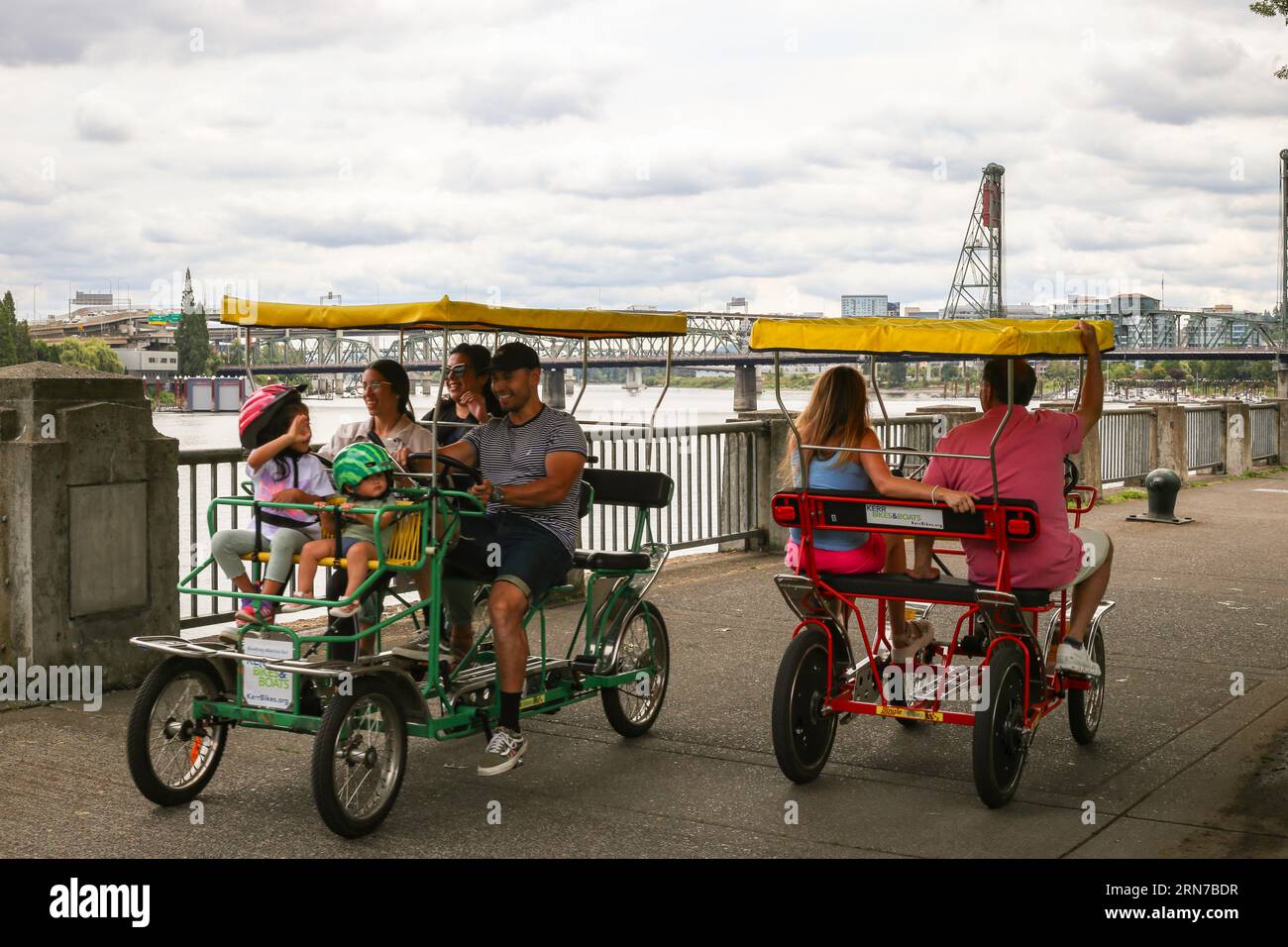Una famiglia felice che passa accanto a una coppia di pedalò noleggiate da Kerr Bikes nel centro di Portland, Oregon Foto Stock
