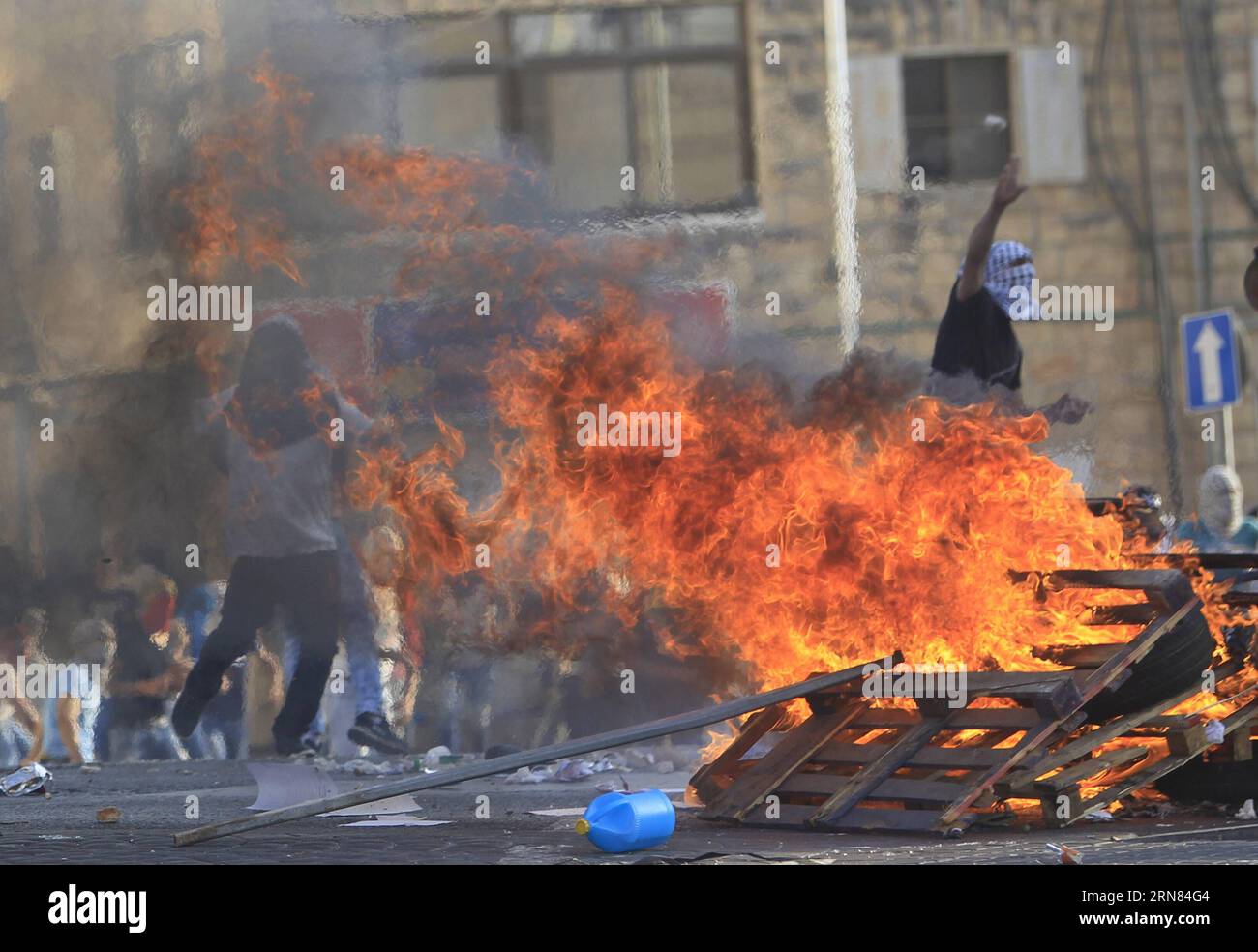 (151005) -- GERUSALEMME, 5 ottobre 2015 -- i manifestanti palestinesi lanciano pietre dietro il legno bruciato durante gli scontri con le forze di sicurezza israeliane nel quartiere di Shuafat, Gerusalemme est, il 5 ottobre 2015. In questi giorni si sono verificati scontri tra palestinesi e coloni ebrei, e tra palestinesi e forze di sicurezza israeliane, che potrebbero segnare l'inizio di una terza intifada (rivolta armata), che ha spinto le forze israeliane a prendere ulteriori misure di sicurezza. MIDEAST-EAST JERUSALEM-CLASHES MuammarxAwad PUBLICATIONxNOTxINxCHN Gerusalemme ottobre 5 2015 manifestanti PALESTINESI gettano pietre dietro Burnin Foto Stock