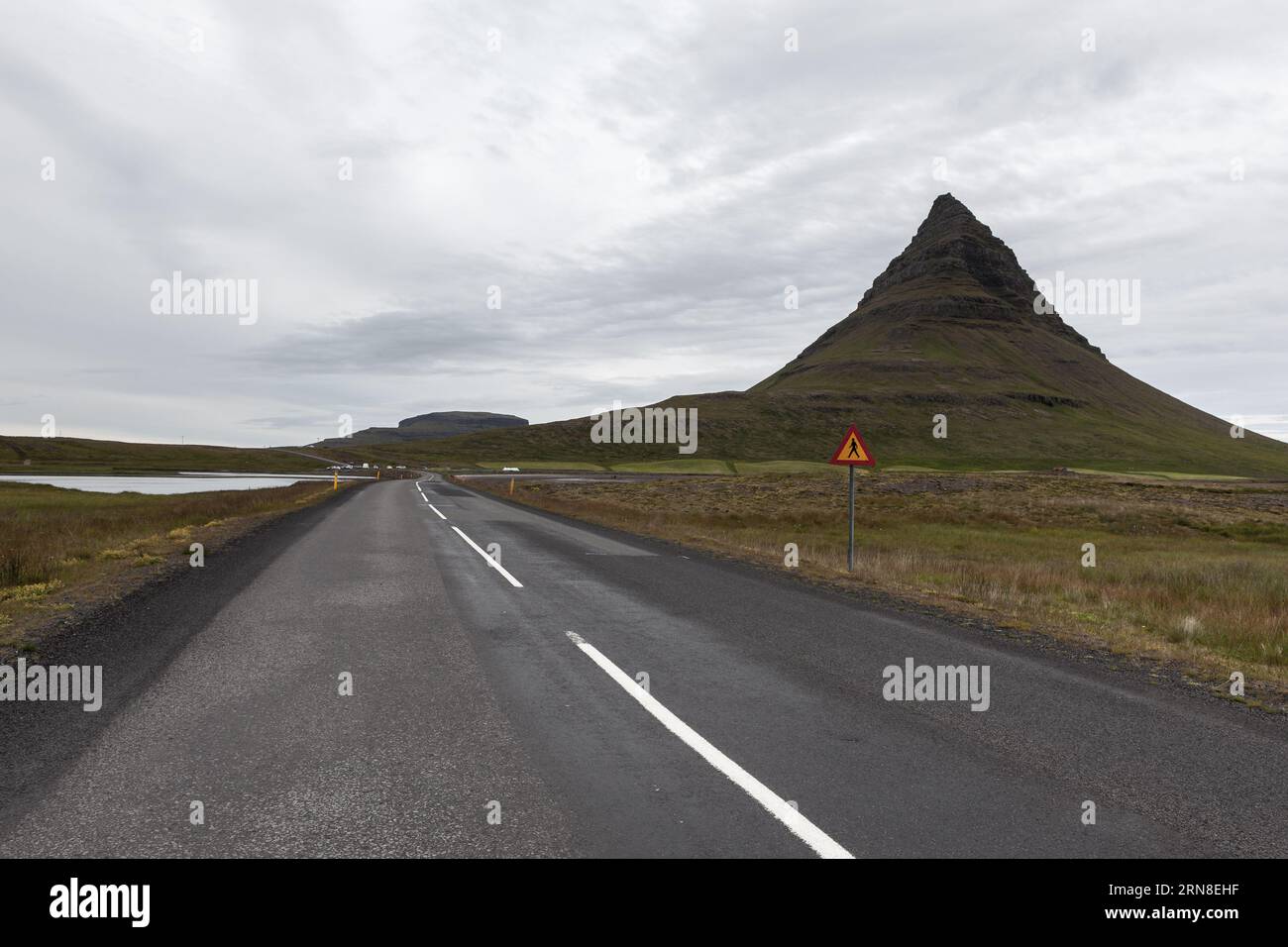 Strada asfaltata vuota che passa accanto al famoso vulcano Kirkjufell. Incredibile paesaggio montano islandese verde. Penisola di Snaefellsnes, Islanda occidentale. Foto Stock