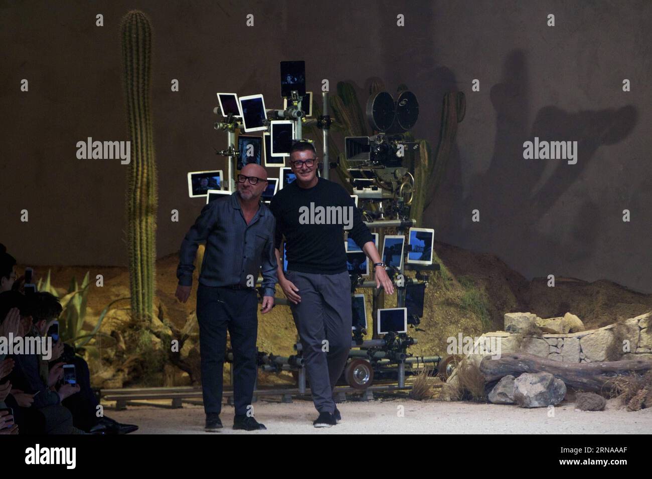 Domenico Dolce (L) e Stefano Gabbana riconoscono gli applausi del pubblico dopo aver presentato la loro collezione di sfilate uomo Dolce & Gabbana autunno-inverno 2016-2017 durante la settimana della moda milanese a Milano, in Italia, il 16 gennaio 2016. Ispirato agli iconici film WESTERN di spaghetti diretti da un regista italiano Sergio Leone negli anni '1960, che ha portato l'industria cinematografica italiana all'attenzione della folla internazionale, la collezione mostra un contrasto tra il passato (attraverso i ricami e le decorazioni del selvaggio West) e il presente (le forme, il taglio e la vestibilità). ITALIA-MILANO-D&G-SETTIMANA DELLA MODA Foto Stock
