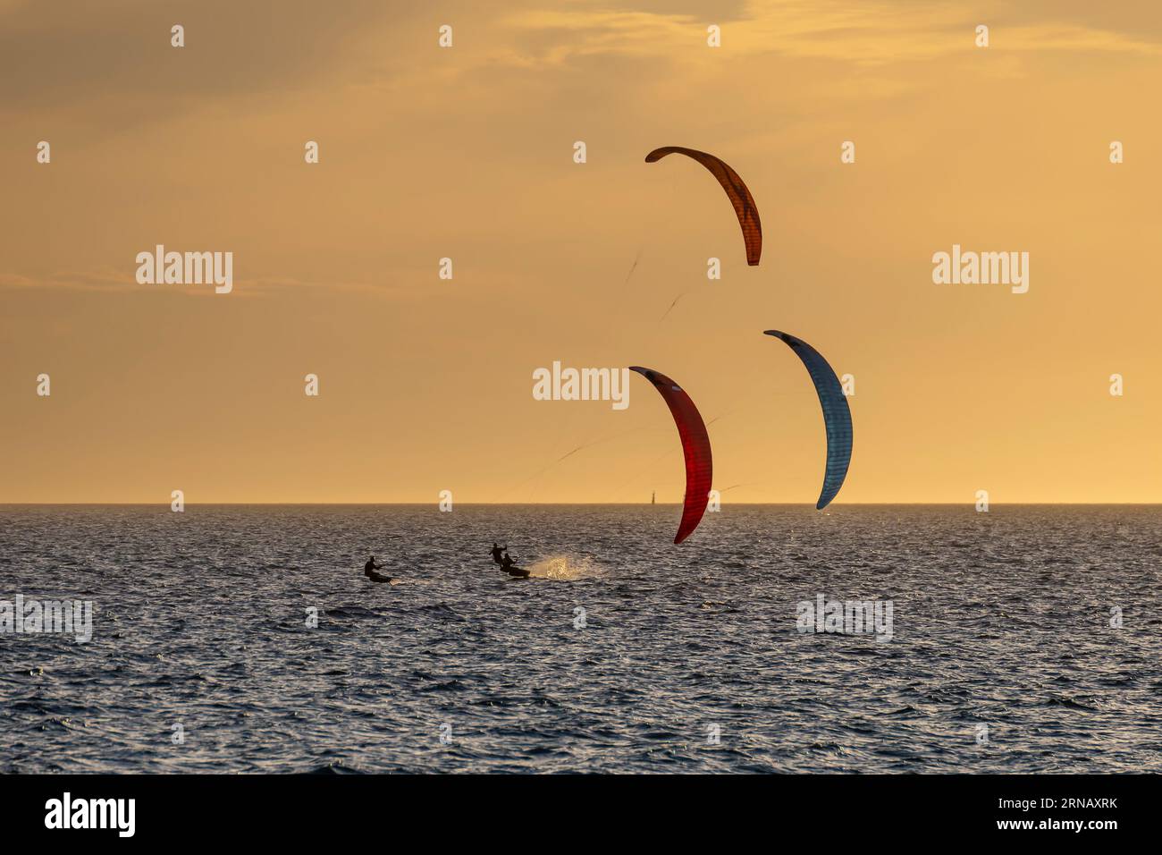 Tre kitesurfisti al tramonto di fronte a Fremantle beach, Australia occidentale Foto Stock