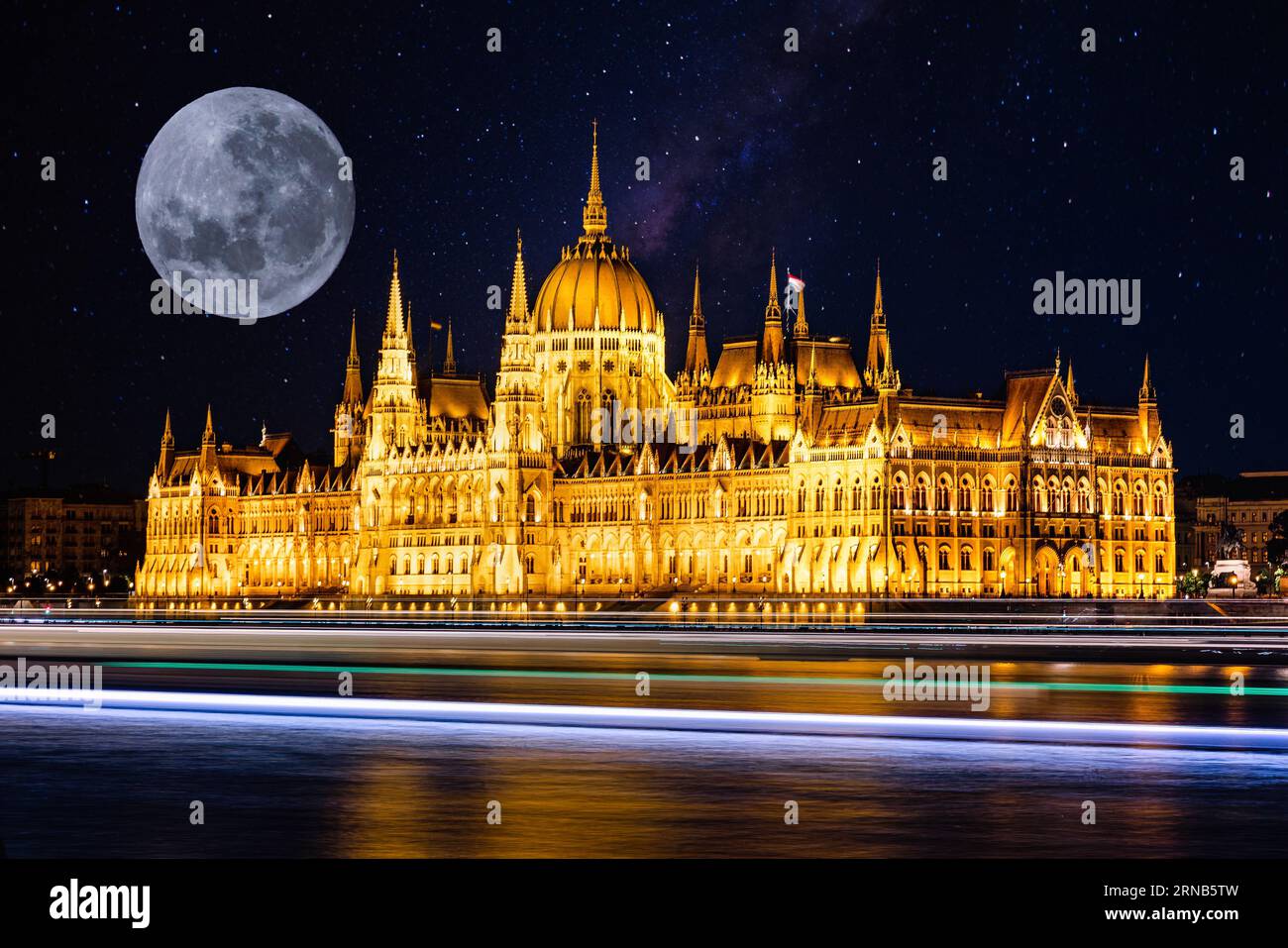 Una luna piena nel cielo notturno sopra l'edificio del Parlamento ungherese, illuminato nell'oscurità Foto Stock