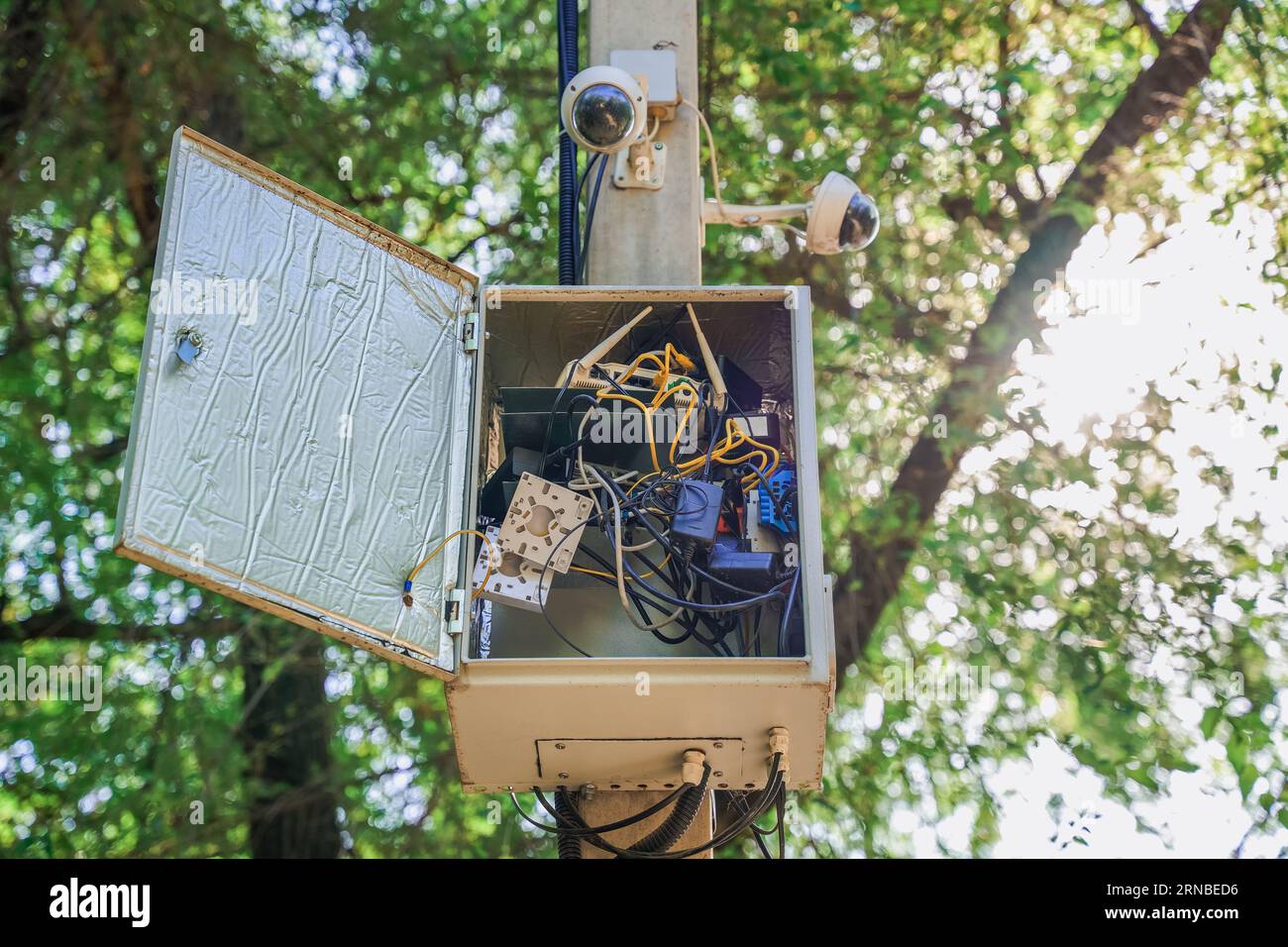 Un quadro di comando CCTV con una porta aperta è appeso a un palo. Controllo di sicurezza Foto Stock