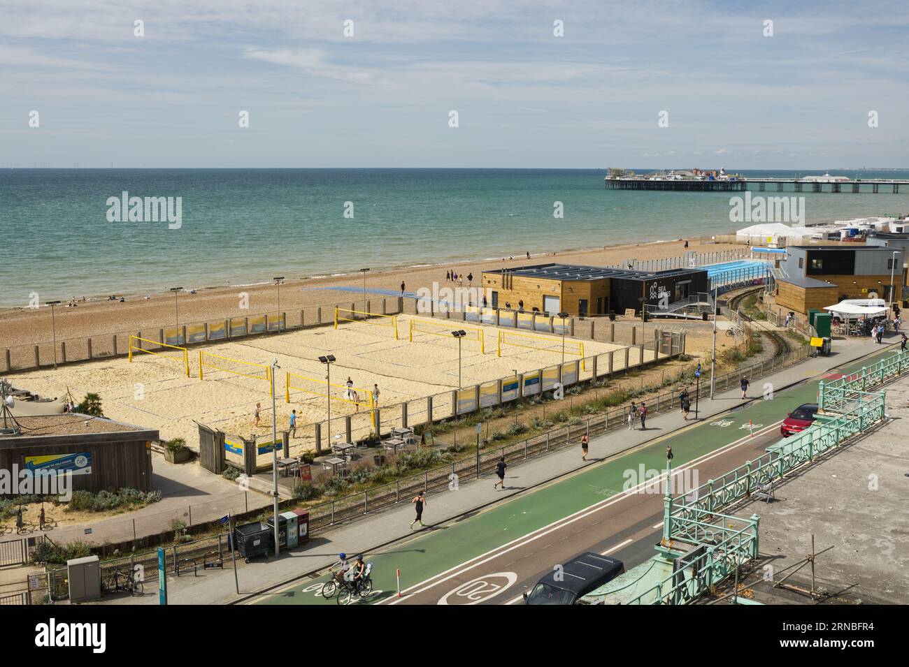 Campo da pallavolo e piscina sulla spiaggia di Brighton nell'East Sussex, Inghilterra. Con il molo del Palazzo sullo sfondo e le persone. Foto Stock