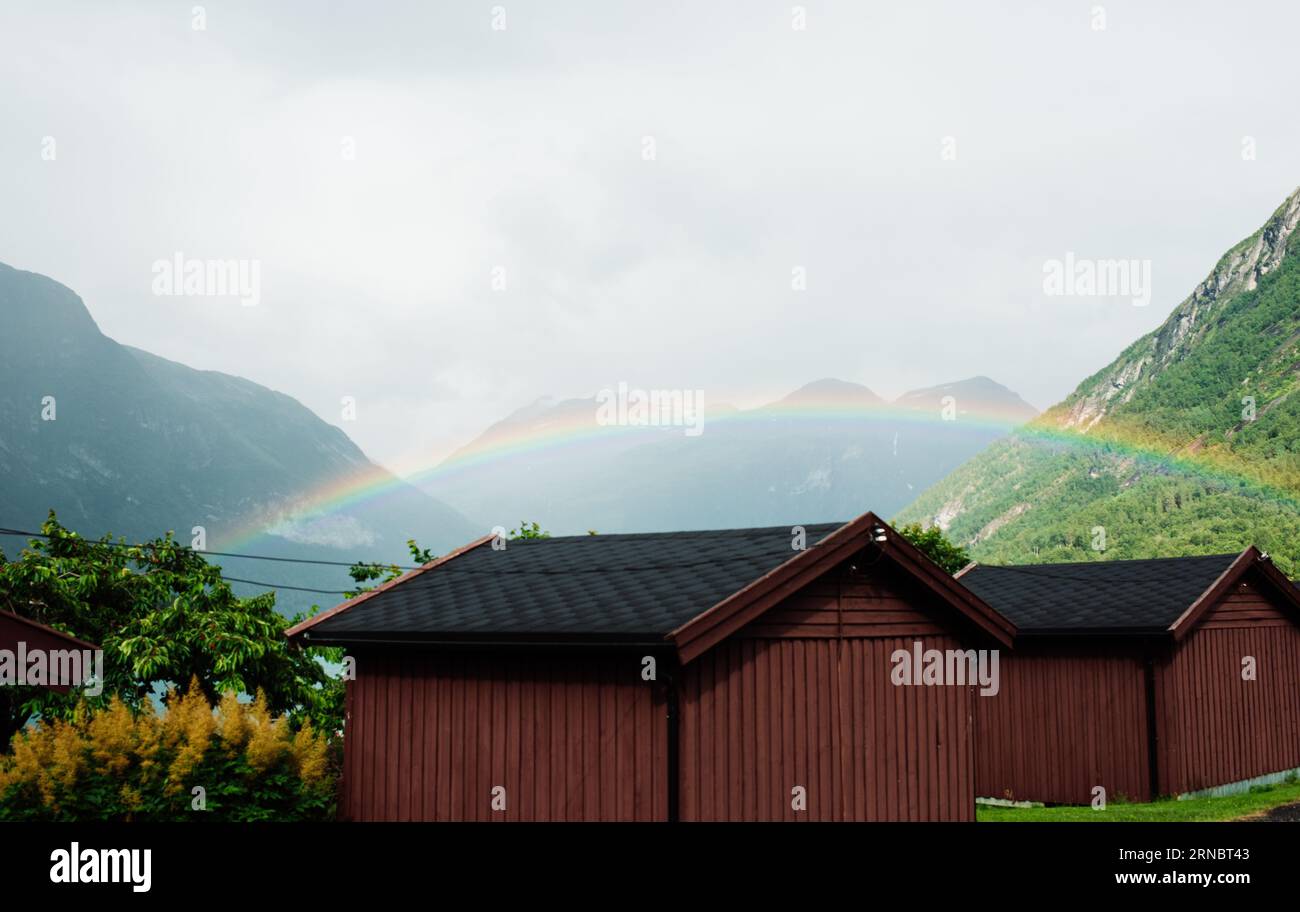 Splendido arcobaleno su un fiordo norvegese e cabine Foto Stock