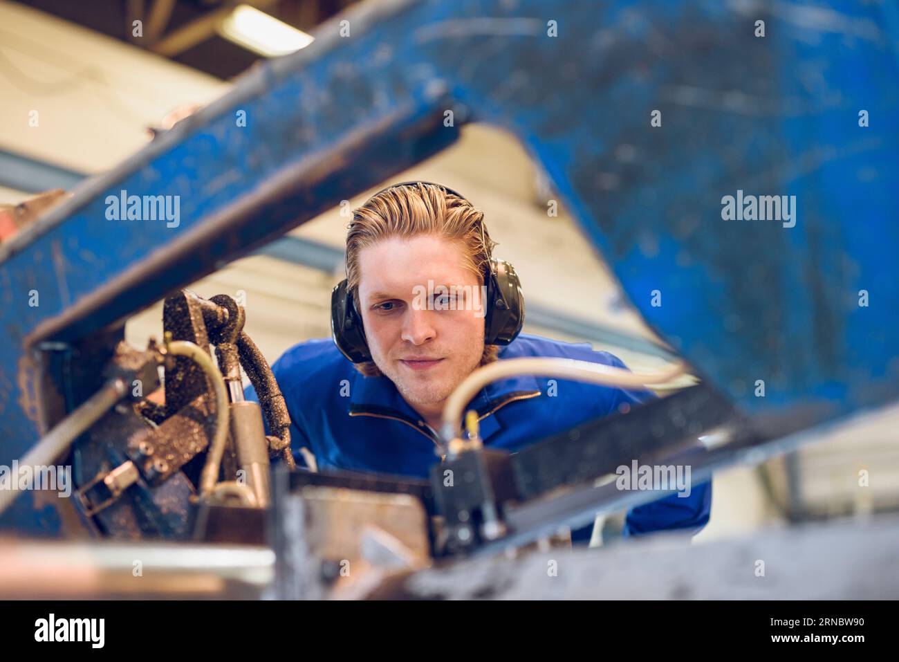 Uomo con cuffie che controlla apparecchiature industriali Foto Stock