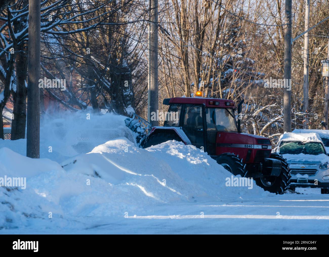 Un gruppo di veicoli viene visto parcheggiato in una strada suburbana, coperta da una fitta coperta di neve. Foto Stock