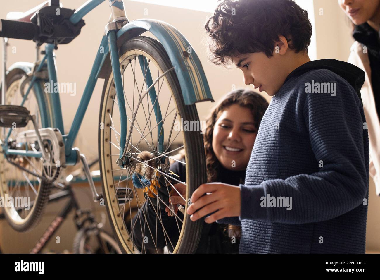 Ragazzo che impara a riparare le biciclette con un tecnico femminile presso il centro di riciclaggio Foto Stock