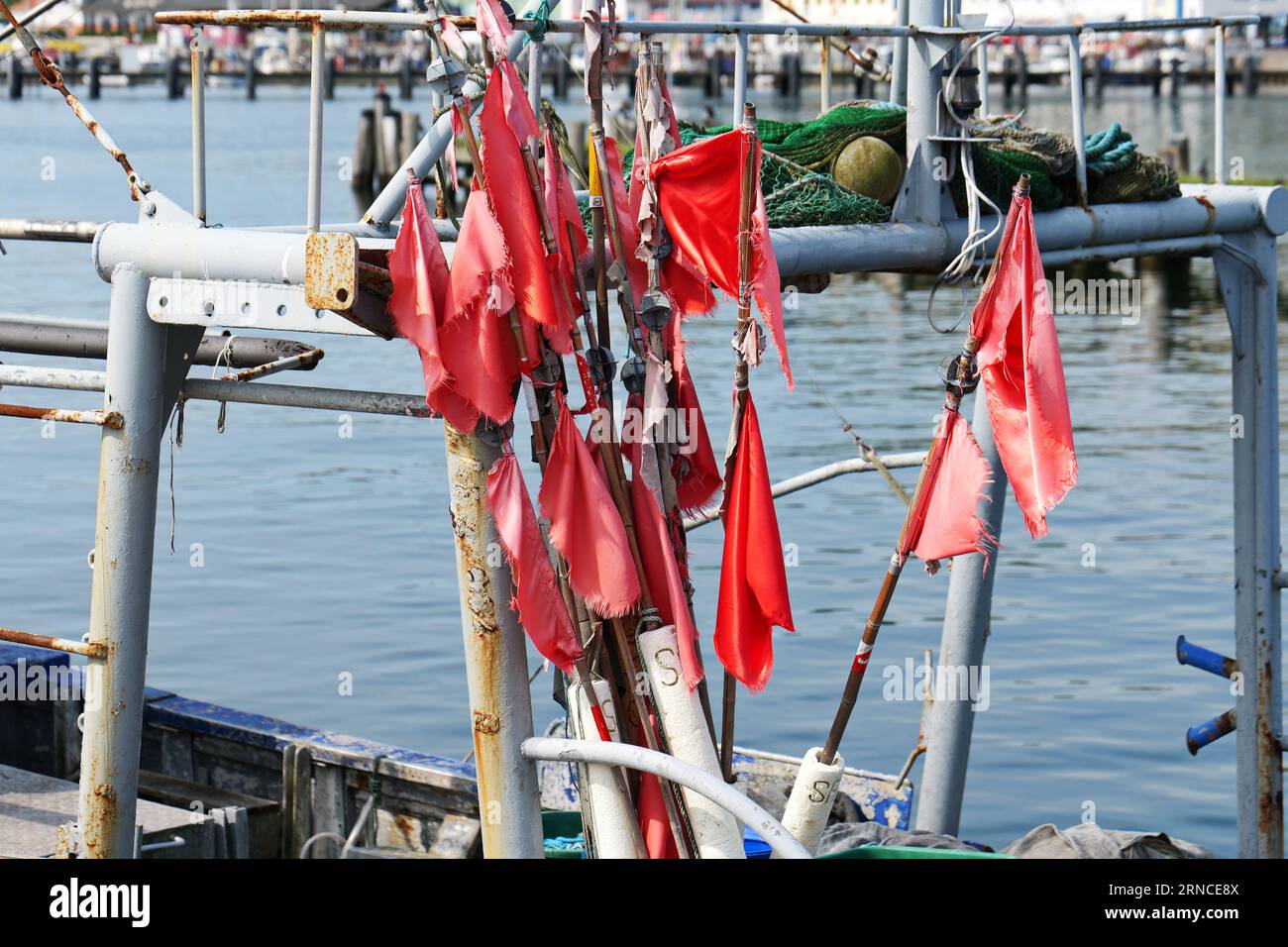 Le bandiere di rete rosse frantumate su una barca da pesca, sopraffatte dai venti bruschi, creano un soggetto fotografico sorprendente. Foto Stock