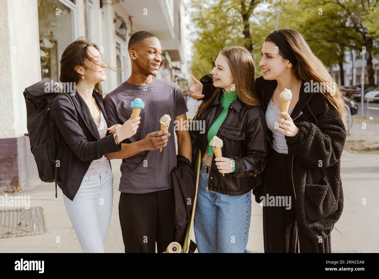 Amici felici che mangiano gelati sul marciapiede Foto Stock