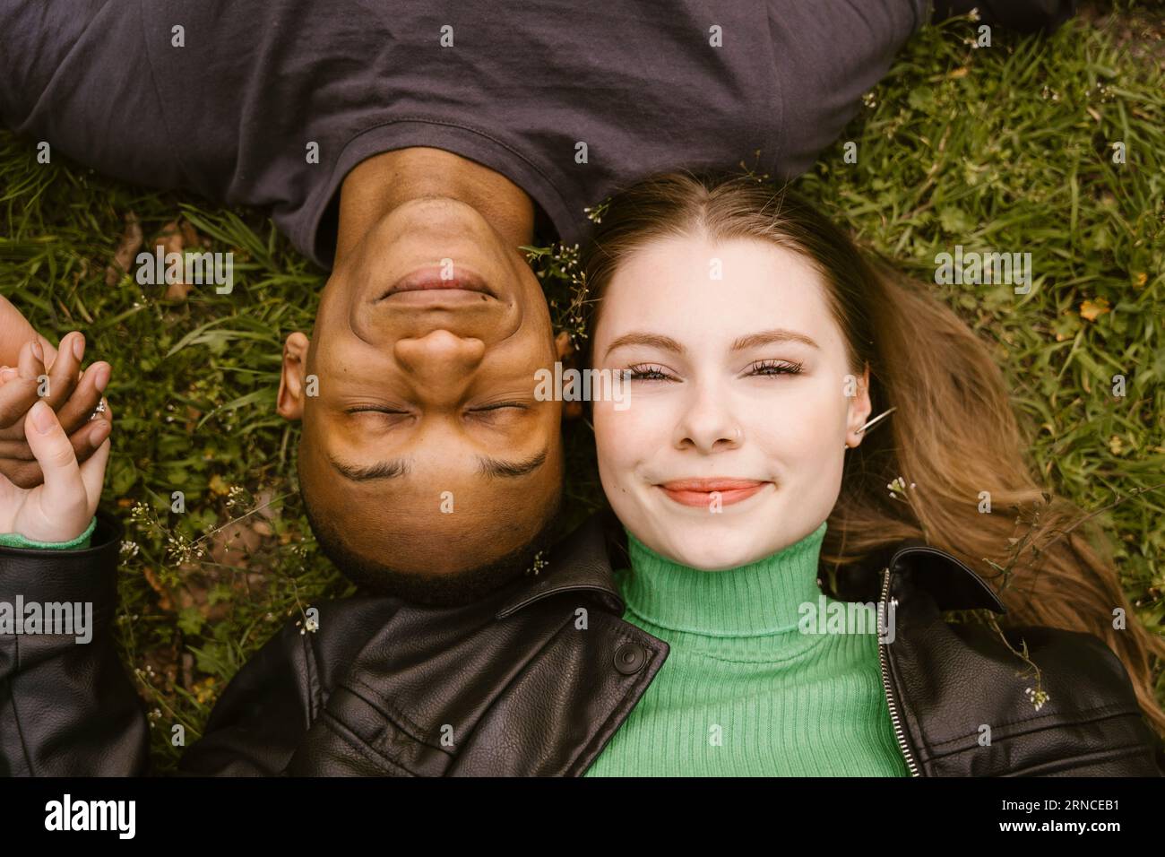 Direttamente sopra la vista di una giovane donna sorridente e di un uomo sdraiato sull'erba Foto Stock