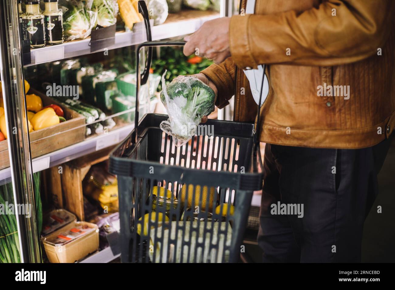La parte centrale dell'uomo anziano che acquista broccoli biologici al negozio di alimentari Foto Stock
