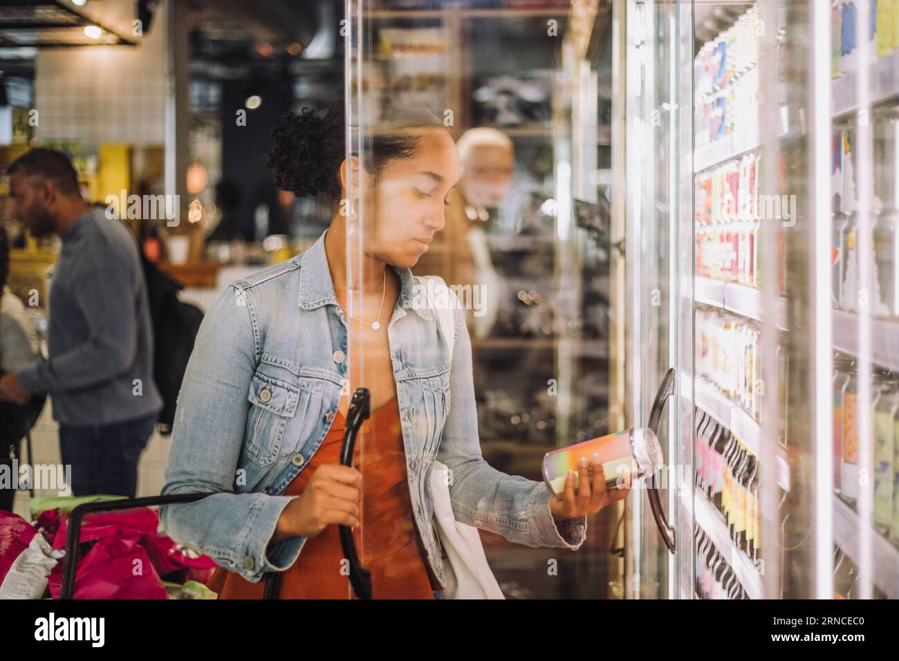 Cliente donna che sta esaminando il vaso mentre si trova in piedi presso un negozio di alimentari Foto Stock