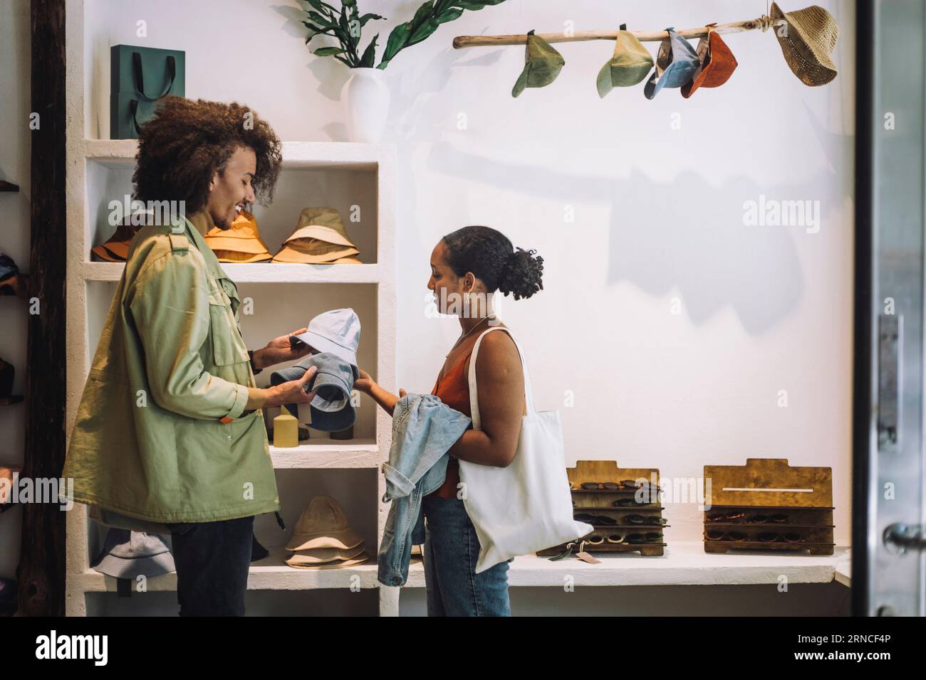 Coppia che compra cappelli mentre sta insieme in una boutique di moda Foto Stock