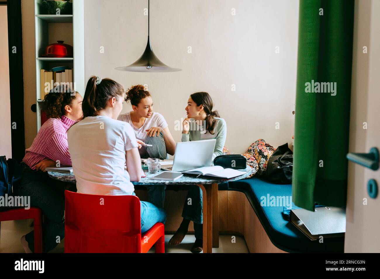 Amiche femminili che discutono mentre studiano insieme a casa Foto Stock