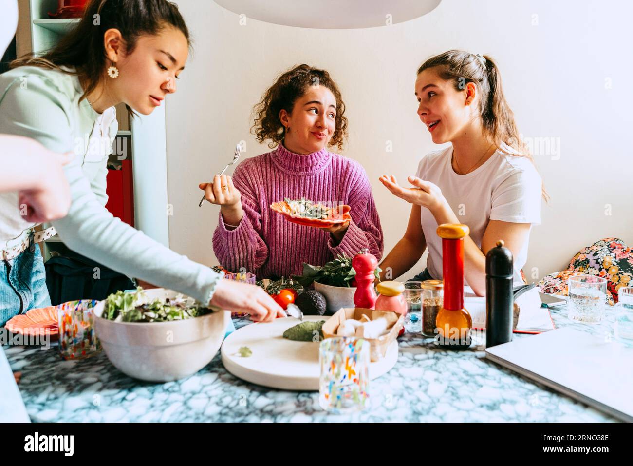 Donna che serve il pranzo mentre le amiche parlano a casa Foto Stock